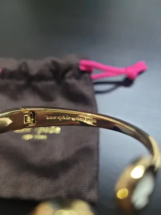 Pulsera rigida Kate Spade dorada con circonita