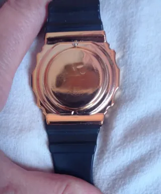 Reloj digital negro con caja dorada.