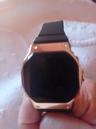 Reloj digital negro con caja dorada.