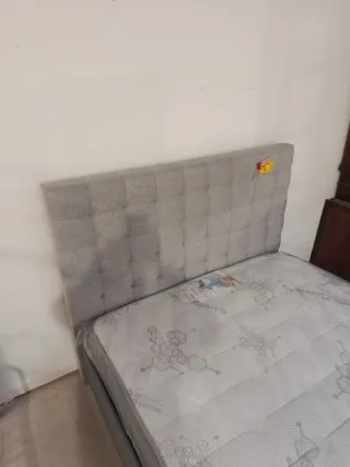 Cama canapé tapizada gris y negra.