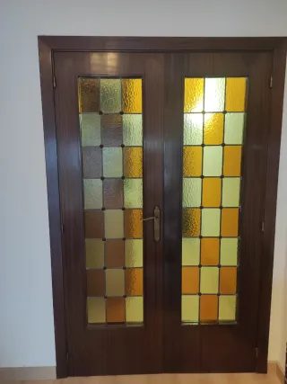 Puertas dobles de madera y cristales emplomados.