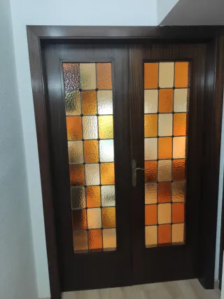 Puertas dobles de madera y cristales emplomados.