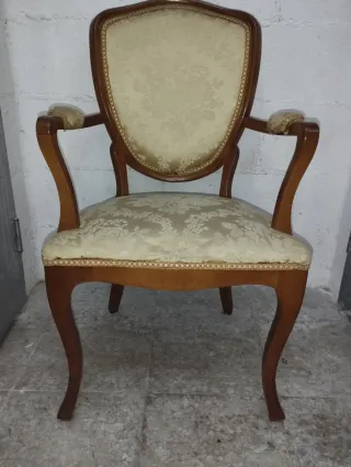 Antigua butaca de madera tapizada estilo clásico