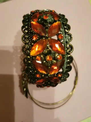 Pulsera brocados y piedras doradas y rojas.