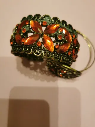 Pulsera brocados y piedras doradas y rojas.