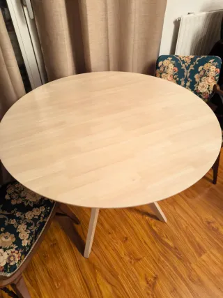 Mesa redonda de madera color beige.