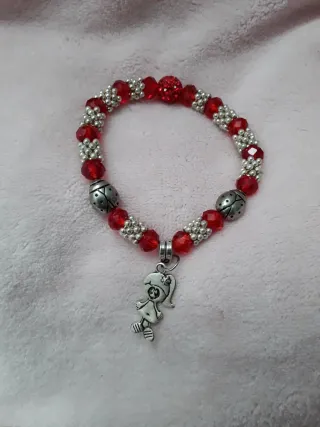 Pulsera con charm de niña y cuentas rojas.