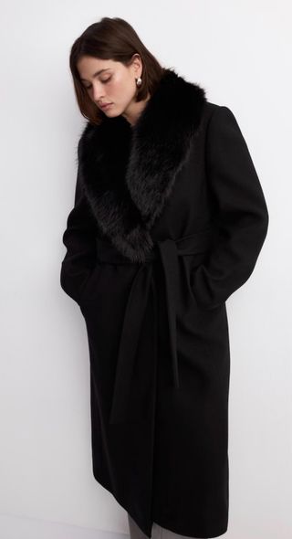 Abrigo largo negro con cuello y mangas de pelo.