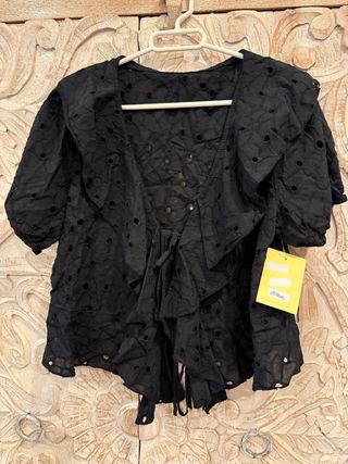 Blusa negra con volantes y lazada