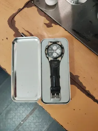 Reloj plateado y negro con su caja