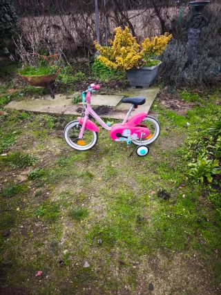 Bicicleta infantil rosa con ruedines.