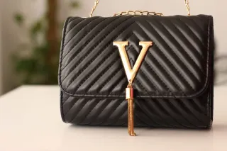 Bolso negro con cadena dorada y detalle V