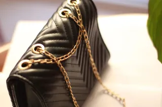 Bolso negro con cadena dorada y detalle V