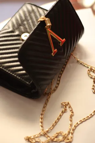 Bolso negro con cadena dorada y detalle V