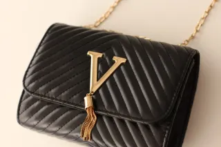 Bolso negro con cadena dorada y detalle V