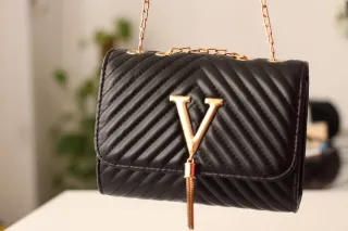 Bolso negro con cadena dorada y detalle V