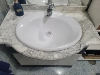 Mueble de baño con lavabo y espejo, con grifo.