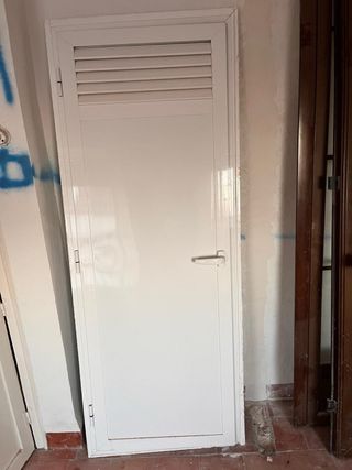 Puerta aluminio blanca con rejilla.