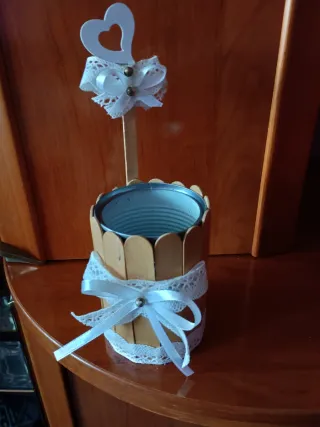 Lata decorada con palitos y lazo blanco