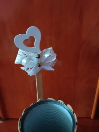 Lata decorada con palitos y lazo blanco
