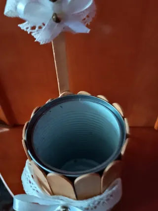 Lata decorada con palitos y lazo blanco