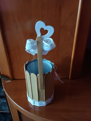 Lata decorada con palitos y lazo blanco