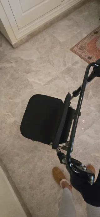 Andador ortopédico con asiento y cesta de compra.