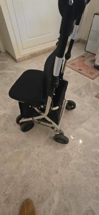 Andador ortopédico con asiento y cesta de compra.