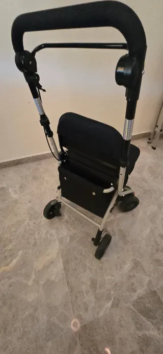 Andador ortopédico con asiento y cesta de compra.