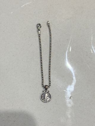 Pulsera plateada con dije religioso