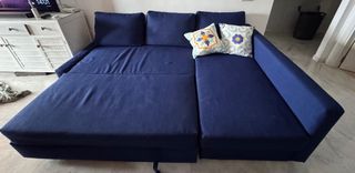 Sofá cama azul con cojines.