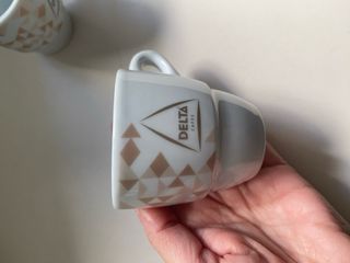 Taza de porcelana blanca Delta con plato a juego.