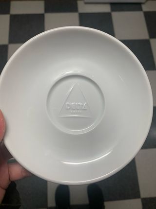 Taza de porcelana blanca Delta con plato a juego.