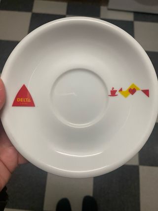 Taza de porcelana blanca Delta con plato a juego.