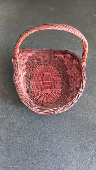 Cesta de mimbre con asa y uvas decorativas.