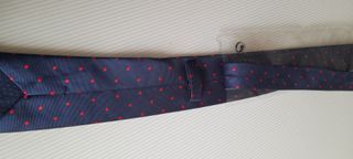 Corbata azul marino con topos rojos.