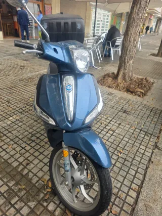 Ciclomotor azul con baúl grande para repartos