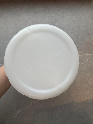 Bote blanco con tapa negra de plástico.