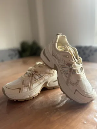 Zapatillas deportivas beige y blancas.