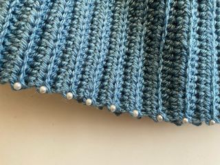 Capa tejida azul con perlas