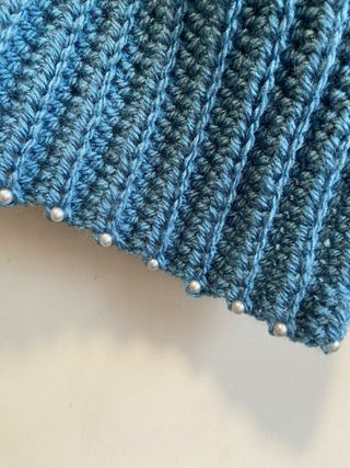 Capa tejida azul con perlas