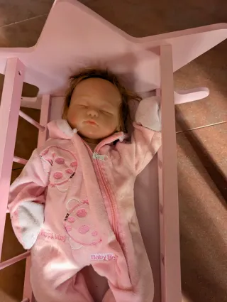 Cuna de bebé rosa con muñeca