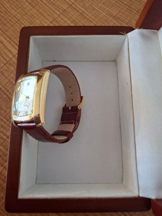 Reloj Thermidor Dorado con correa de cuero rojo.