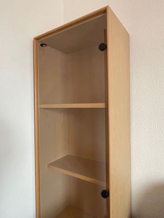 Vitrina en madera clara y puerta de cristal.