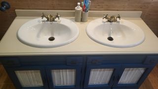 Mueble de baño azul con lavabos y grifos