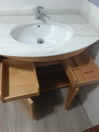 Mueble de baño con espejo, lavabo y grifo.