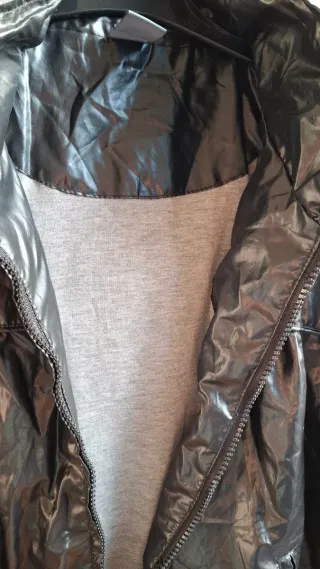 Chaqueta negra con capucha, tipo chubasquero.