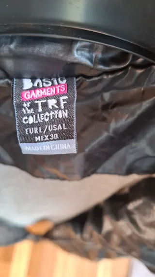 Chaqueta negra con capucha, tipo chubasquero.