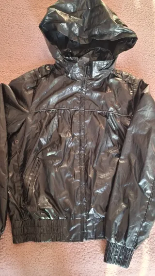 Chaqueta negra con capucha, tipo chubasquero.