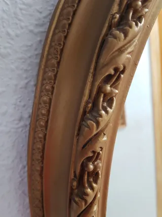 Espejo ovalado con marco decorativo dorado